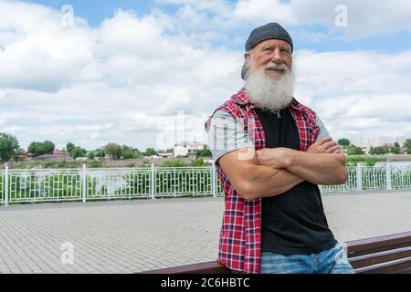 Vieux expérimenté avec barbe dans la rue posant et souriant, portrait Banque D'Images