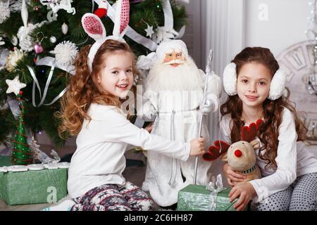 Petites filles dans des vêtements confortables de maison assis sur le sol dans de belles décorations de Noël. Deux petites sœurs décorant l'arbre de Noël avec du sapin-co Banque D'Images