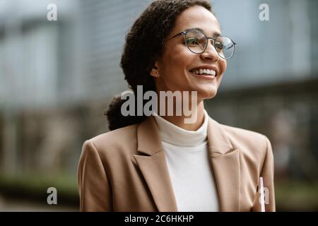 Belle femme d'affaires qui marche sur la route. Femme d'affaires avec lunettes sur la rue de ville. Banque D'Images