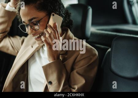 Femme d'affaires assise dans sa voiture et parlant au téléphone. Femme en tenue d'affaires qui fait un appel téléphonique en étant assise dans sa voiture. Banque D'Images