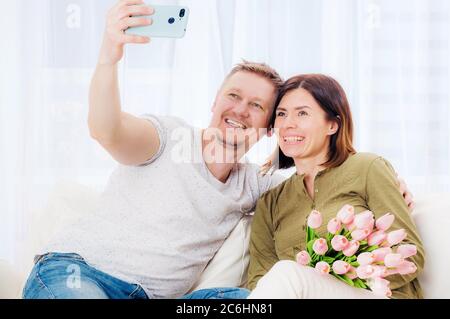 Couple de famille prenant selfie avec bouquet de fleurs sur mobile Banque D'Images
