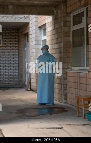 Personne en costume de protection debout à l'extérieur près du bâtiment. Concept de pandémie. Hôpital de la ville. Mai 2020, Brovary, Ukraine Banque D'Images
