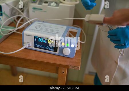 Le médecin mesure la fréquence cardiaque et le niveau de saturation en oxygène dans le sang du patient. Équipement médical. Main humaine avec élément de capteur d'oxymètre de pouls attaché Banque D'Images