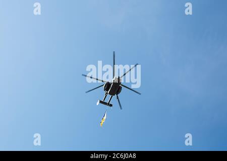 Petit hélicoptère civil avec drapeau ukrainien vole contre un ciel bleu avec fond de nuages, région de Kiev, Ukraine Banque D'Images