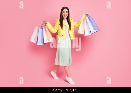 Photo pleine longueur de jolie dame contenir de nombreux packs de shopping acheter nouvelle collection vêtements habits tendance jaune cuir veste long chaussures de jupe isolées Banque D'Images