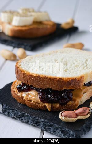 restauration rapide, encas, deux sandwichs à la confiture de beurre d'arachide et bananes sur une table en bois blanc Banque D'Images