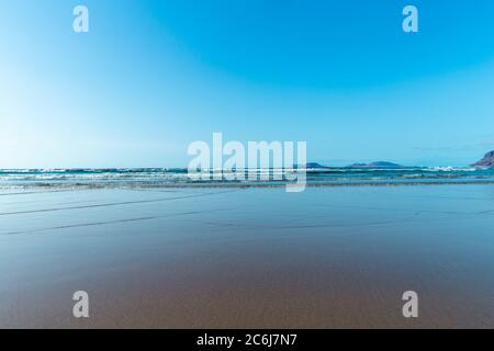 Panorama de la belle plage et de la mer tropicale de Lanzarote. Canaries. Côte de la plage de Famara, île de Lanzarote, îles Canaries. Touristes sur le plus pop Banque D'Images