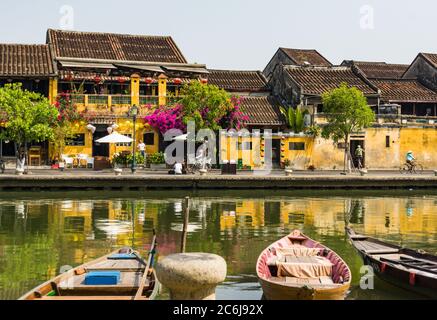 Scène de la vieille ville historique de Hoi an le long de la rivière avec des bateaux, lanternes, fleurs et les bâtiments jaune or Hoi an avec des toits de tuiles Banque D'Images
