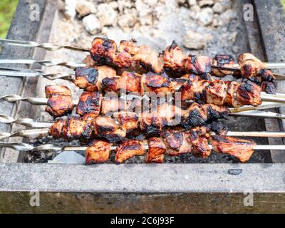 pile de kebabs de shish cuits (shashlyk) provenant du porc sur le brasier extérieur (concentration sur les kebabs au premier plan) Banque D'Images
