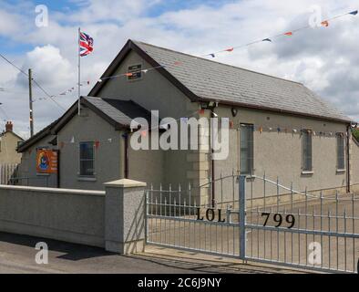 Broomhaie, Comté d'Antrim, Irlande du Nord. 10 juillet 2020. Météo britannique – averses légères mais fréquentes et soleil dus à une brise du nord-ouest. Une salle orange rurale en Irlande du Nord avec drapeau Union Jack volant à côté de rouge blanc et bleu bunting au soleil. En raison de Covid 19 il n'y aura pas de manifestations annuelles du 12 juillet par des pavillons orange dans quelques jours, mais les bandes peuvent décider de défilé - la commission des parades a vu plus de 200 demandes dans les derniers jours . Crédit : CAZIMB/Alamy Live News. Banque D'Images