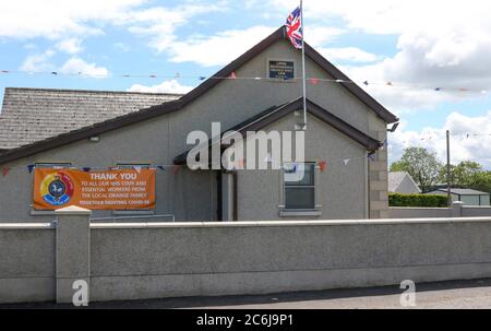 Broomhaie, Comté d'Antrim, Irlande du Nord. 10 juillet 2020. Météo britannique – averses légères mais fréquentes et soleil dus à une brise du nord-ouest. Une salle orange rurale en Irlande du Nord avec drapeau Union Jack volant à côté de rouge blanc et bleu bunting au soleil. En raison de Covid 19 il n'y aura pas de manifestations annuelles du 12 juillet par des pavillons orange dans quelques jours, mais les bandes peuvent décider de défilé - la commission des parades a vu plus de 200 demandes dans les derniers jours . Crédit : CAZIMB/Alamy Live News. Banque D'Images