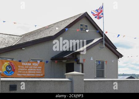 Broomhaie, Comté d'Antrim, Irlande du Nord. 10 juillet 2020. Météo britannique – averses légères mais fréquentes et soleil dus à une brise du nord-ouest. Une salle orange rurale en Irlande du Nord avec drapeau Union Jack volant à côté de rouge blanc et bleu bunting au soleil. En raison de Covid 19 il n'y aura pas de manifestations annuelles du 12 juillet par des pavillons orange dans quelques jours, mais les bandes peuvent décider de défilé - la commission des parades a vu plus de 200 demandes dans les derniers jours . Crédit : CAZIMB/Alamy Live News. Banque D'Images