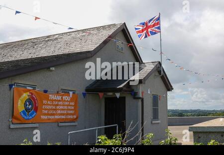 Broomhaie, Comté d'Antrim, Irlande du Nord. 10 juillet 2020. Météo britannique – averses légères mais fréquentes et soleil dus à une brise du nord-ouest. Une salle orange rurale en Irlande du Nord avec drapeau Union Jack volant à côté de rouge blanc et bleu bunting au soleil. En raison de Covid 19 il n'y aura pas de manifestations annuelles du 12 juillet par des pavillons orange dans quelques jours, mais les bandes peuvent décider de défilé - la commission des parades a vu plus de 200 demandes dans les derniers jours . Crédit : CAZIMB/Alamy Live News. Banque D'Images