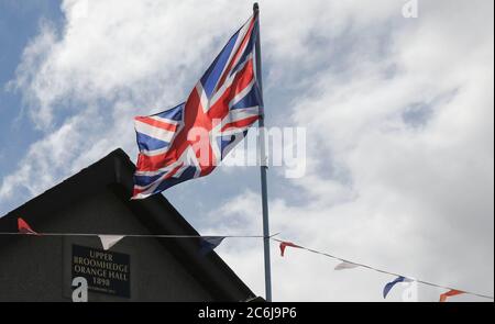 Broomhaie, Comté d'Antrim, Irlande du Nord. 10 juillet 2020. Météo britannique – averses légères mais fréquentes et soleil dus à une brise du nord-ouest. Une salle orange rurale en Irlande du Nord avec drapeau Union Jack volant à côté de rouge blanc et bleu bunting au soleil. En raison de Covid 19 il n'y aura pas de manifestations annuelles du 12 juillet par des pavillons orange dans quelques jours, mais les bandes peuvent décider de défilé - la commission des parades a vu plus de 200 demandes dans les derniers jours . Crédit : CAZIMB/Alamy Live News. Banque D'Images