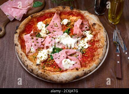 Pizza italienne avec mortadelle et fromage sur une table en bois sombre. Une alimentation saine Banque D'Images