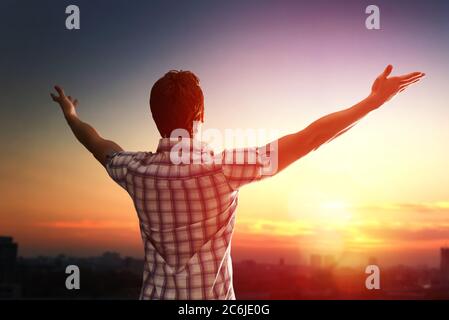 Homme réussi regardant le ciel du coucher du soleil célébrant la liberté. Émotion humaine positive sentiment vie perception succès, concept de la tranquillité d'esprit. F Banque D'Images