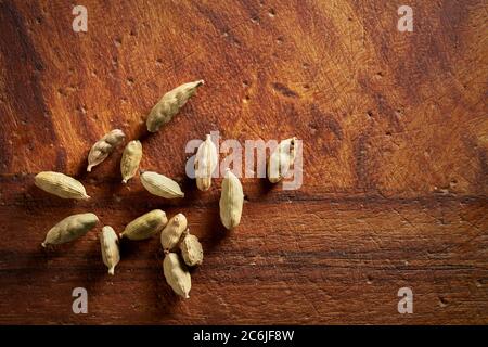 Gousses de cardamome séchées sur un vieux panneau en bois. Banque D'Images