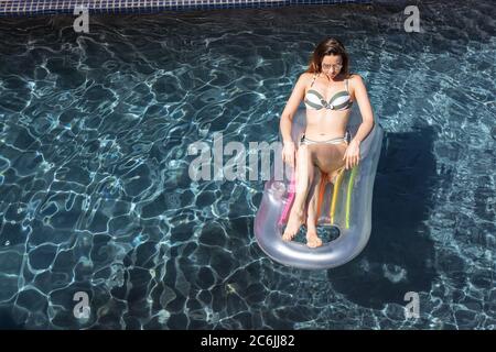 Femme flottant sur l'anneau gonflable dans la piscine Banque D'Images