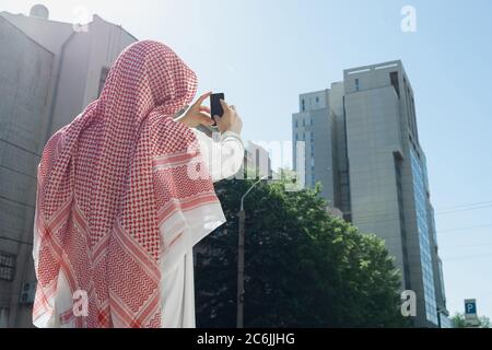 Riche portrait d'homme arabe lors de l'achat de biens immobiliers, centre d'affaires en ville. Ethnicité, culture, inclusion. Homme d'affaires confiant dans les vêtements traditionnels faisant une affaire réussie. Finances, économie. Banque D'Images