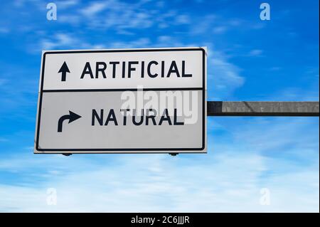 Artificiel contre naturel. Deux panneaux de signalisation blancs avec flèche sur poteau métallique. Route directionnelle, panneau de chemin Crossroads, deux flèches. Fond bleu ciel. Banque D'Images