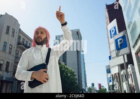 Riche portrait d'homme arabe lors de l'achat de biens immobiliers, maison de vie en ville. Ethnicité, culture, diversité. Homme d'affaires confiant dans les vêtements traditionnels faisant une affaire réussie. Finances, économie. Banque D'Images