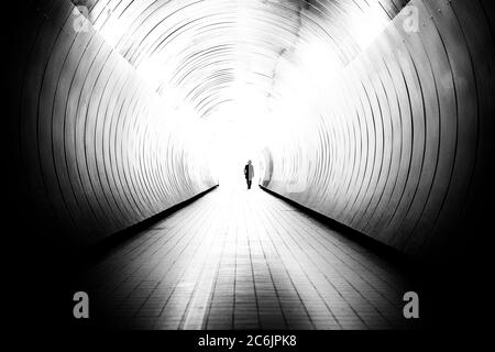 La perspective décroissante de l'homme méconnaissable dans un tunnel public lumineux à Stockholm, en Suède. Le tunnel est un chemin de promenade entre deux rues. Banque D'Images