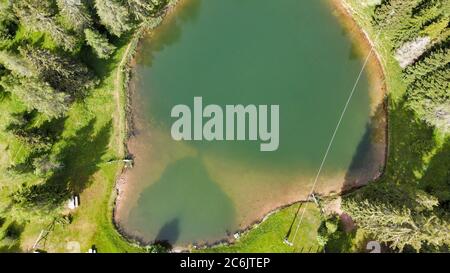 Lac alpin en été entouré par une belle forêt, vue aérienne en hauteur. Banque D'Images