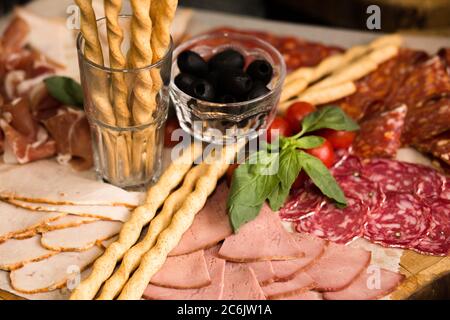 Assortiment de tranches de viande avec gressins et olives sur planche en bois. Gros plan. Cadeaux de vacances ou d'événements. Restauration concept alimentaire. Concept antipasti Banque D'Images