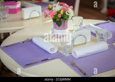 Un décor lumineux de célébration sur une table ronde avec bouquet de roses dans un café attend ses invités. Concept romantique. Concept d'événement ou de fête Banque D'Images