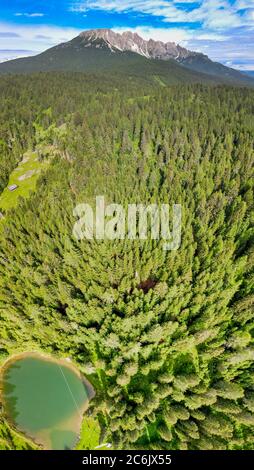 Lac alpin en été entouré par une belle forêt, vue aérienne en hauteur. Banque D'Images