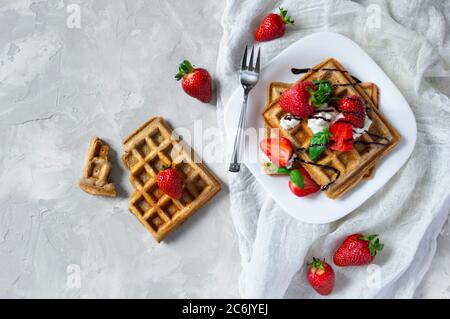 Gaufres belges carrées faites maison avec fraises, ricotta et chocolat sur une assiette blanche. Pose à plat. Banque D'Images