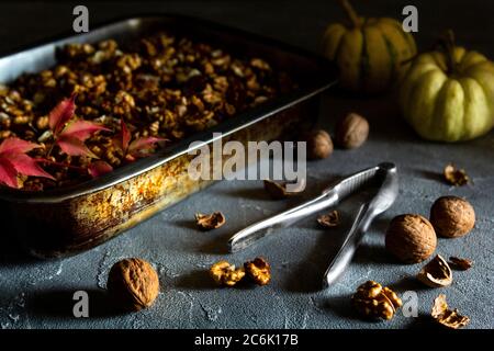 Noix entières et coupées en deux dans une casserole avec casse-noisette et citrouilles sur fond sombre. Banque D'Images