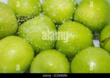 Lavage des fruits. Des pommes mouillées dans la douche et des gouttes d'eau. Banque D'Images