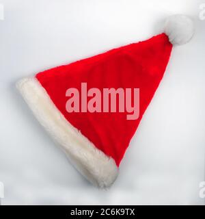 Chapeau de père Noël sur fond blanc avec espace de copie dans la partie supérieure et inférieure de la photo. Photo grand angle de chapeau rouge de Noël flou placée en diagonale. Banque D'Images