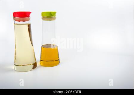 Deux décanteurs d'huile modernes avec couvercles en plastique. Un couvercle est rouge et un couvercle vert lime. Les bouteilles contiennent de l'huile d'olive et de l'huile de tournesol. Les conteneurs sont Banque D'Images