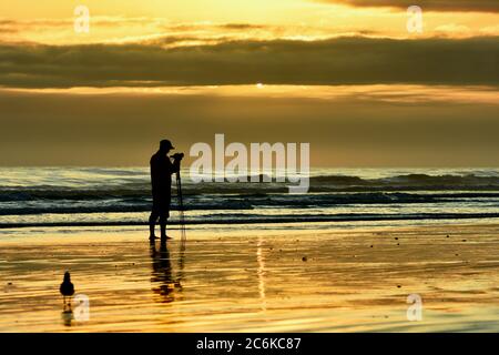 Un photographe non identifié prenant des photos d'un coucher de soleil sur la mer Banque D'Images