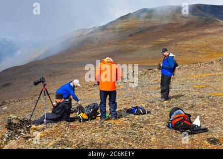 Les photographes se détendent dans un champ de schiste de haute montagne en attendant un ramassage en hélicoptère Banque D'Images