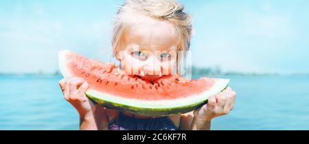 Petite fille en lunettes de soleil roses avec grand segment de pastèque drôle de portrait. Image de concept de saine alimentation. Banque D'Images