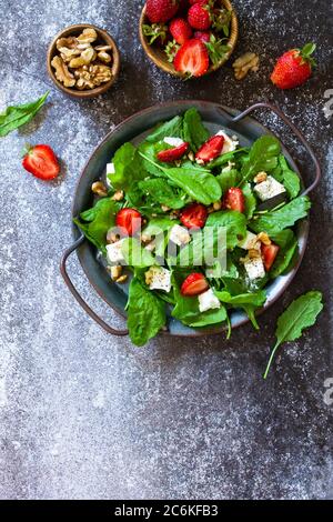 Concept alimentaire sain, assiette à salade. Salade d'été avec fraises, fetacheese et noix sur un comptoir en pierre. Vue de dessus de l'arrière-plan de la mise à plat COP