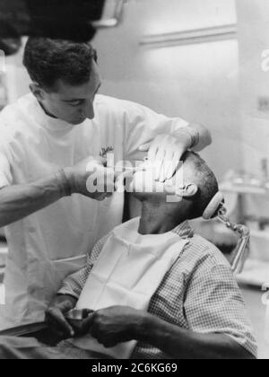 Philadelphie, Pennsylvanie. Circa.1960 - Un dentiste utilise des pinces sur un jeune patient masculin. Banque D'Images