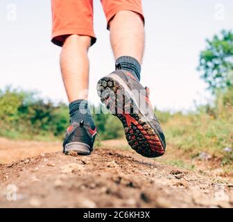 Trekking chaussure semelle gros plan image voyageur pieds dans des bottes de trekking sur la montagne sale chemin à l'été.vue arrière. Banque D'Images