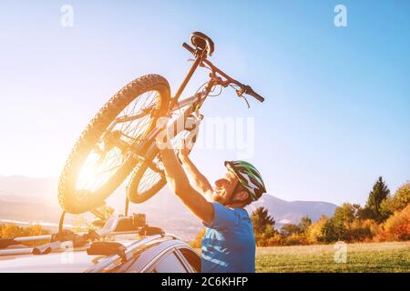 Homme motard de montagne prendre de son vélo devant le toit de voiture. Image de concept de sport actif Banque D'Images