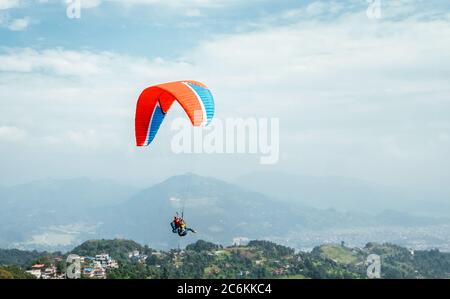 Parapente avec instructeur utilisant le parapente coloré au-dessus de la ville de Pokhara, Népal. Image de concept de vacances actives. Banque D'Images