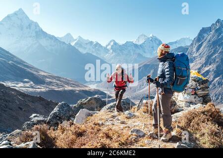 Couple suivant l'itinéraire de randonnée Everest base Camp près de Dughla 4620m. Backpackers portant des sacs à dos et en utilisant des bâtons de randonnée et appréciant la vue sur la vallée Banque D'Images