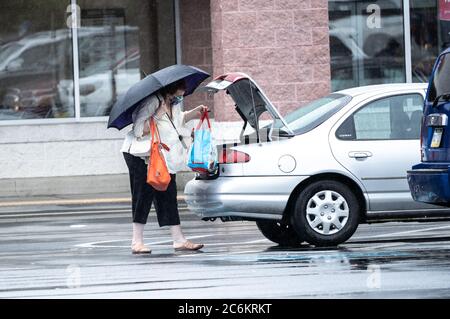 Comté de Berks, Pennsylvanie - 10 juillet 2020 : femme âgée, portant un masque facial, charge des métiers dans le coffre de voiture le jour des pluies. Banque D'Images