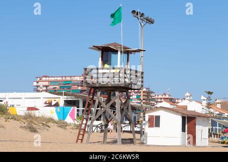 Punta Umbria, Huelva, Espagne - 9 juillet 2020 : un maître de sauvetage assis sur la tour de surveillance de la plage de Punta Umbria, Huelva, Espagne Banque D'Images