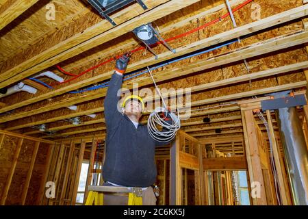 Processus de travail sur les fils électriques lors de l'installation des fils électriques dans le chantier de construction de la nouvelle maison Banque D'Images