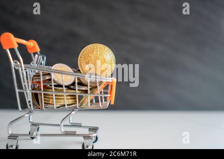 Le symbole Bitcoin ou crypto-monnaie dans le modèle de mini-panier plein de pièces d'argent avec le fond de pièce noire d'espace de copie. Banque D'Images