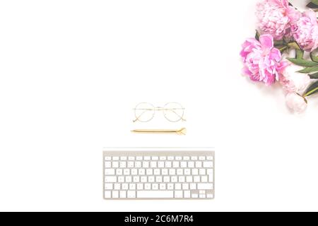 Clavier, stylo doré, lunettes et bouquet de pivoines roses sur fond blanc. Сopy espace. Banque D'Images