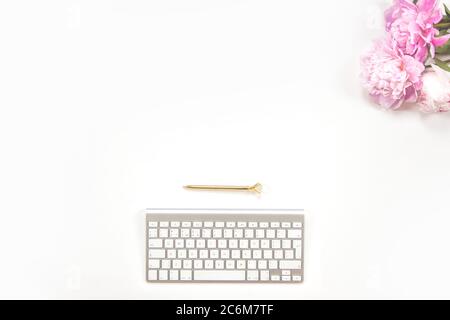 Clavier, stylo doré et bouquet de pivoines roses sur fond blanc. Сopy espace. Banque D'Images